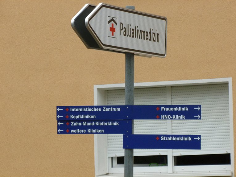 Ein Wegweiser Schild. Ganz oben in Pfeilform die Palliativmedizin Erlangen.